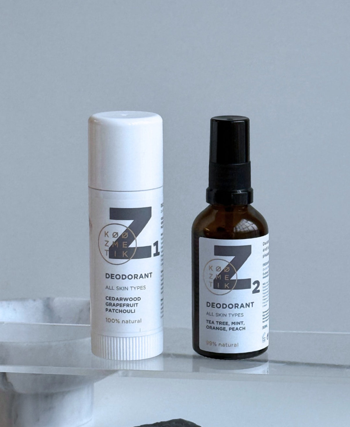 Two deodorant bottles from the brand 'Z' on a marble surface with a light gray background.